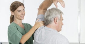 woman therapist assisting older man with arm stretch mobility