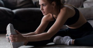 hurdler's pose stretch being practiced by a woman in workout clothing