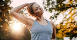 woman performing neck stretch by gently pulling top of head to one side with her hand
