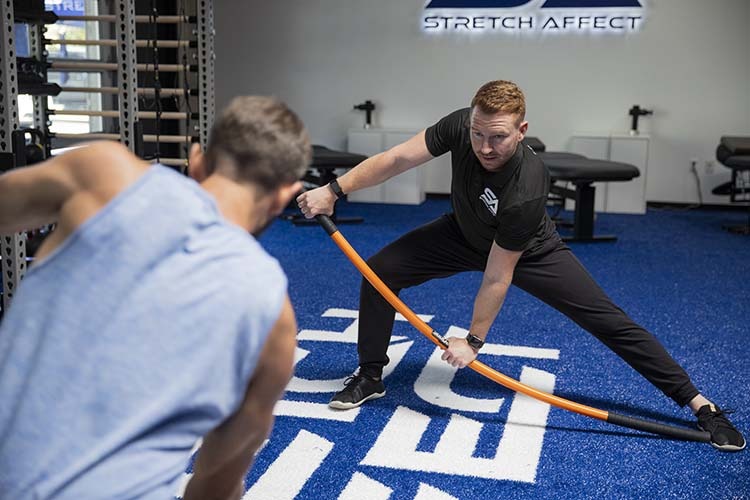 instructor demonstrates stick mobility exercise