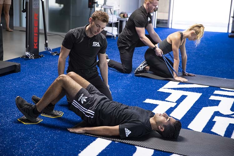 gym with two professional mobility trainers informing two clients in various exercises