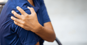 Young person in need of stretches for shoulder pain grabs shoulder in pain.