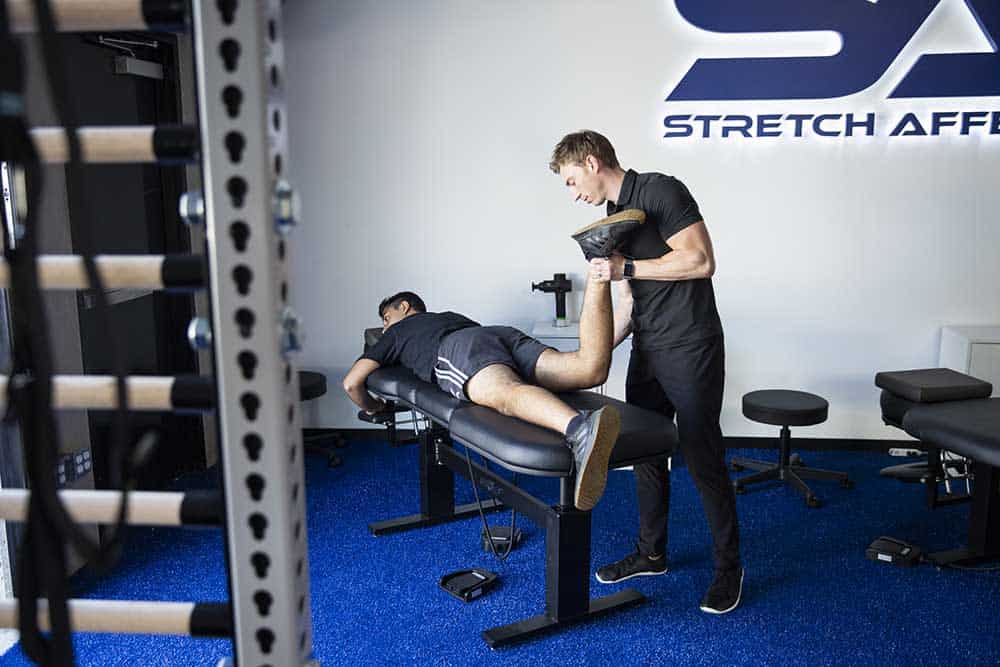 stretching professional assessing leg tightness with client laying on stomach