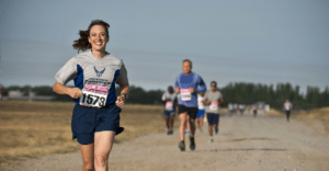 smiling woman running a race ahead of several other participants