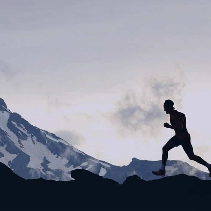 silhouette of man running by mountains